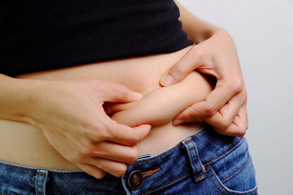 A woman grabbing onto abdominal fat.
