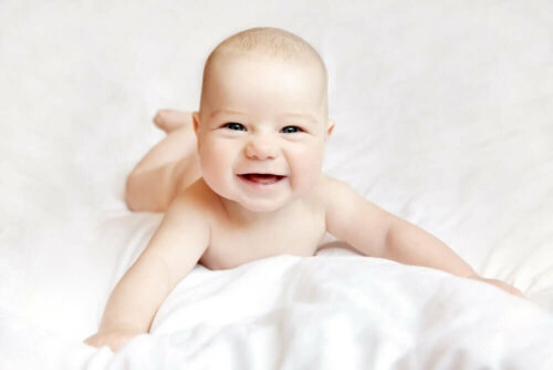 naked baby happy on a duvet