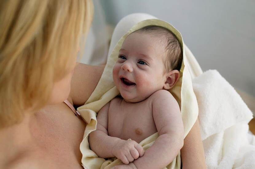 baby smiling up at his mother