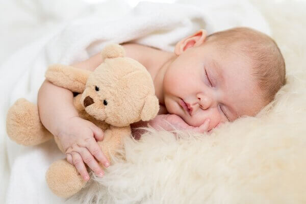 A sleeping baby with a teddy bear.