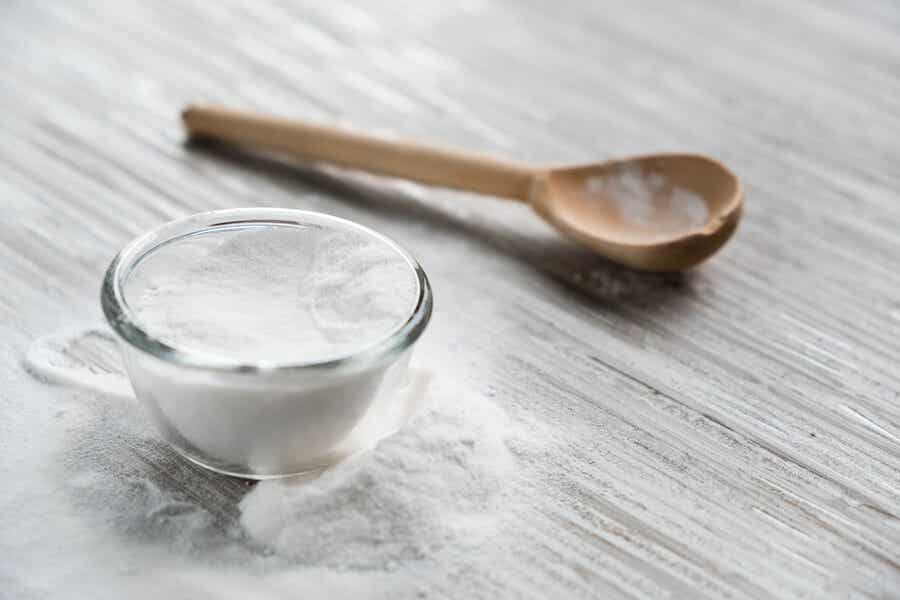 baking soda in a glass jar on a table with a wooden spoon