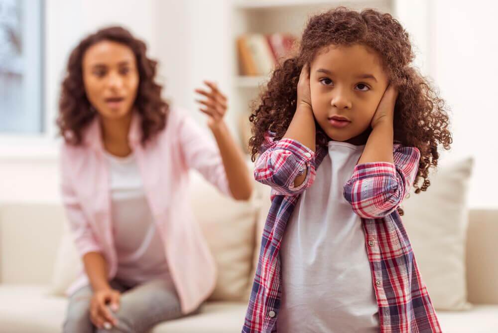 child covering her ears to ignore her mother