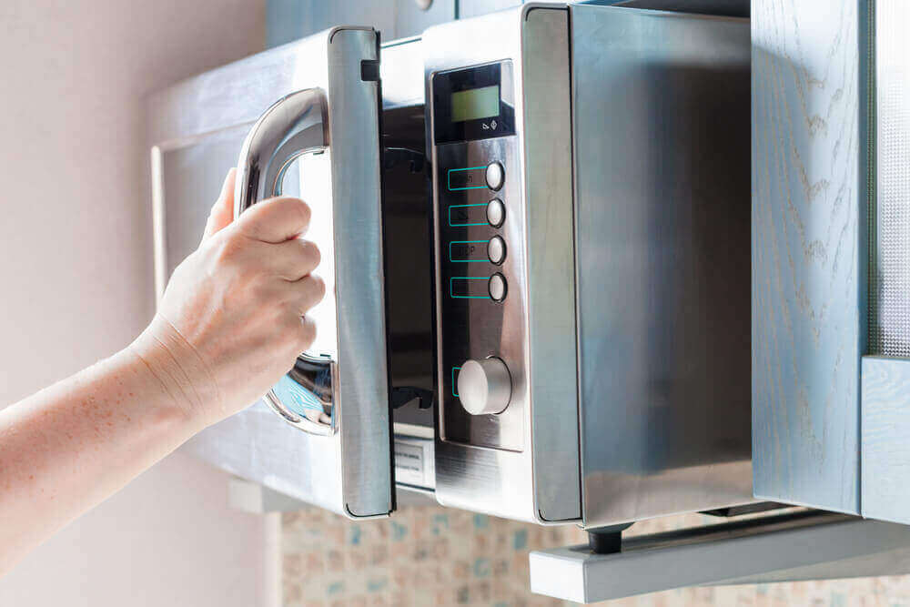 A hand opening a clean microwave.