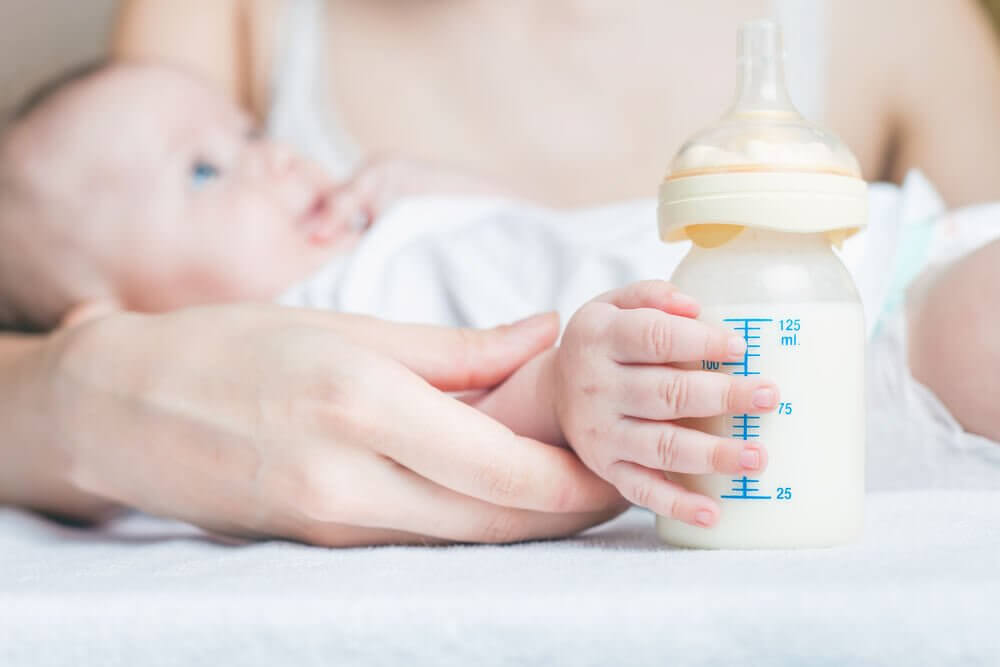 A close up of a baby bottle with a baby in the background