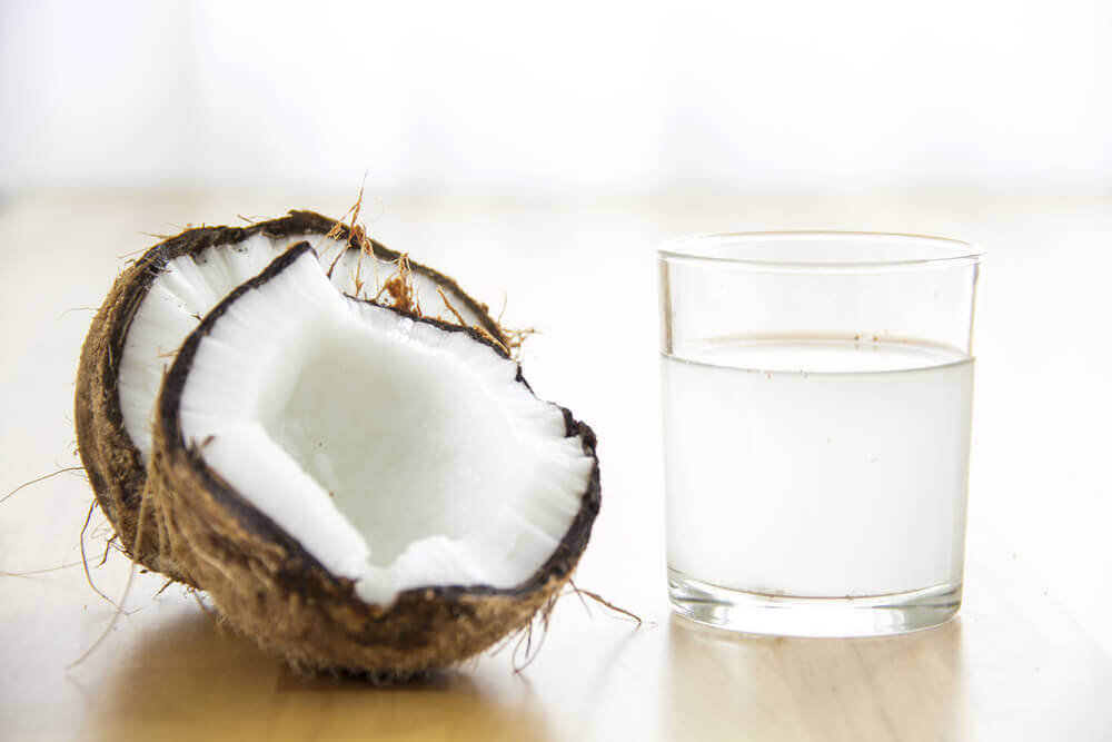 An open coconut and a glass of coconut water.