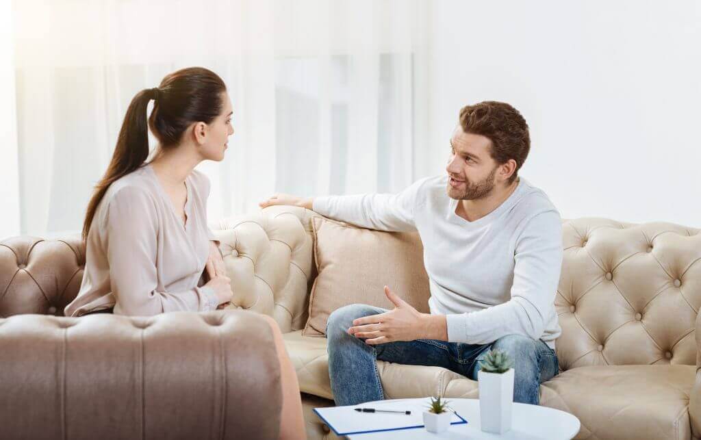 A couple talking on a couch.