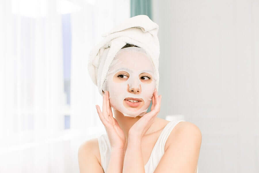 A woman applying a face mask.