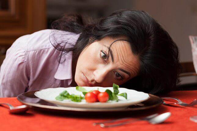 A hungry woman staring at a plate of food.