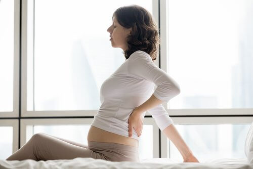 A pregnant woman holding her back.