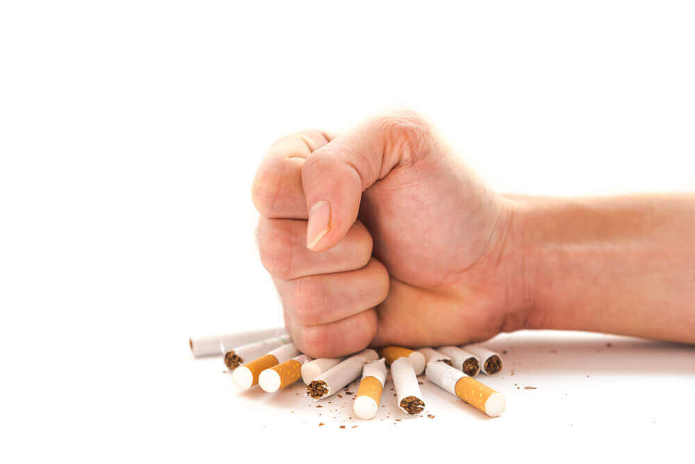 A hand smashing a pile of cigarettes.