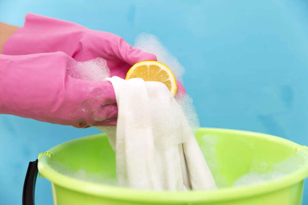 A woman handwashing white clothes with lemon.