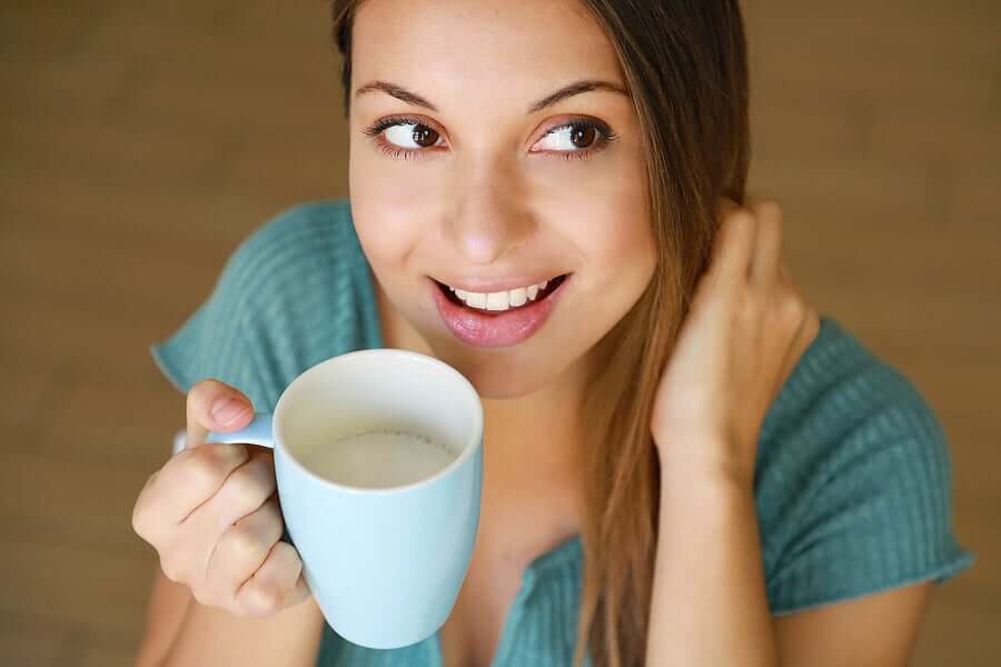 A woman drinking a cup of quinoa milk.
