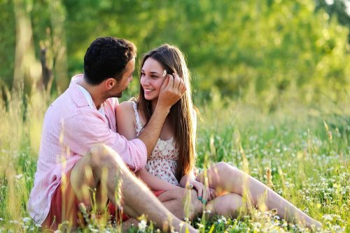 Happy couple sitting on the grass sharing love messages