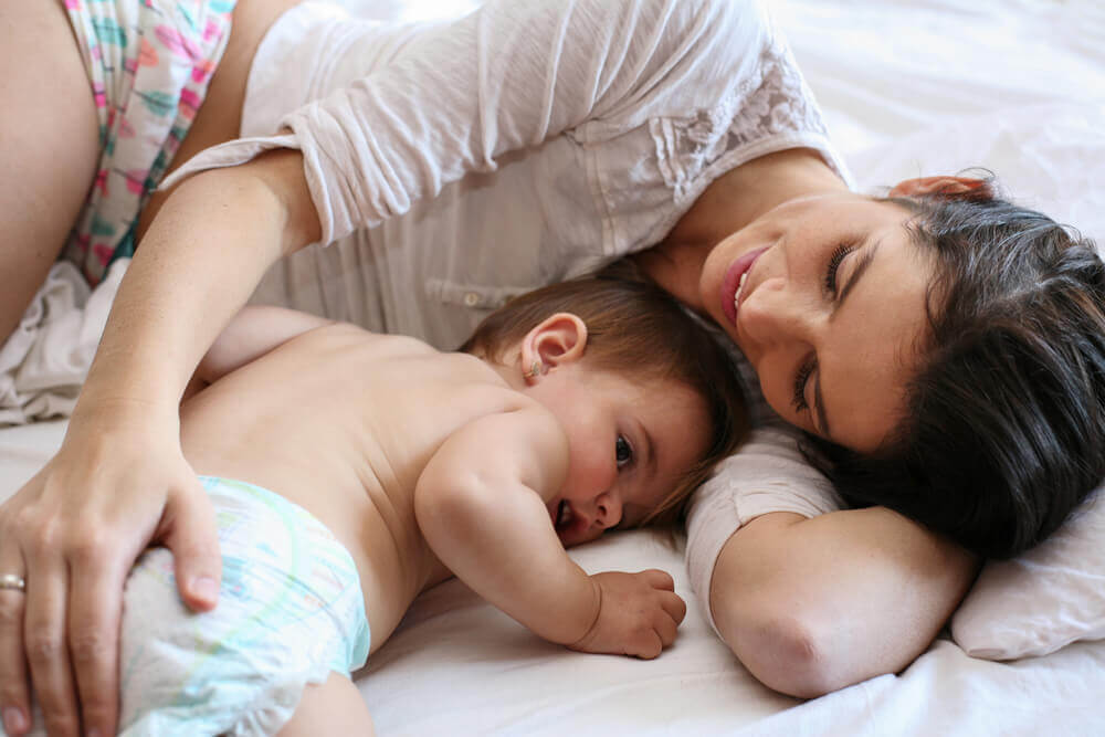 Single mother lying next to baby, being a single mother
