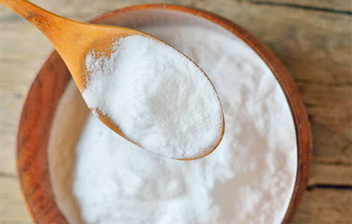 Spoon and bowl of baking soda which can be used in a remedy for oesophagitis