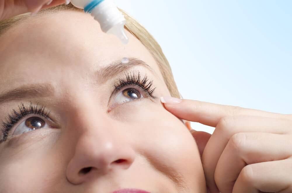 Woman applying eye drops to treat dry eyes which are one of the effects of air conditioning
