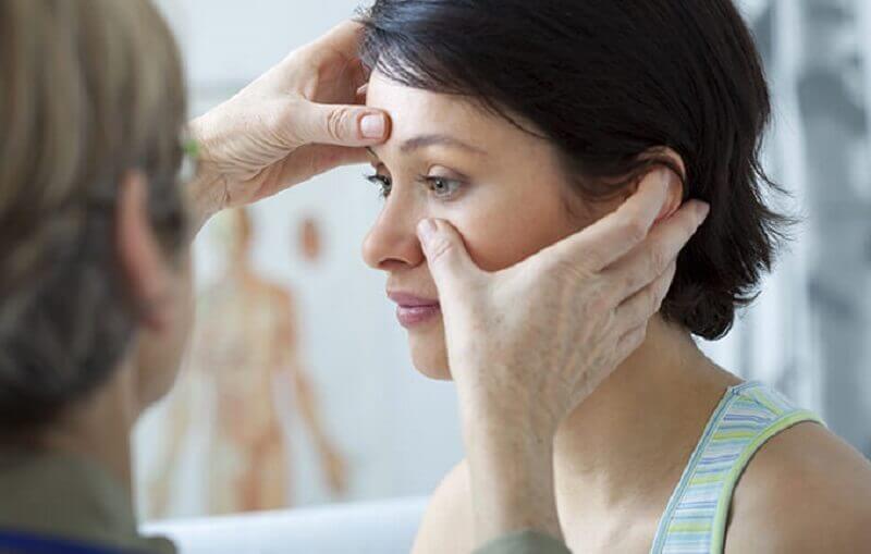 A doctor examining a woman for nasal polyps.