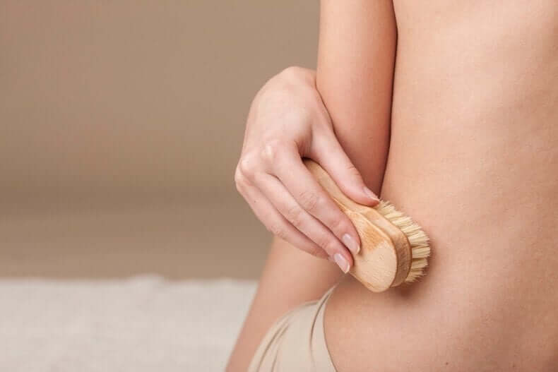 A woman using a dry brush on her skin.