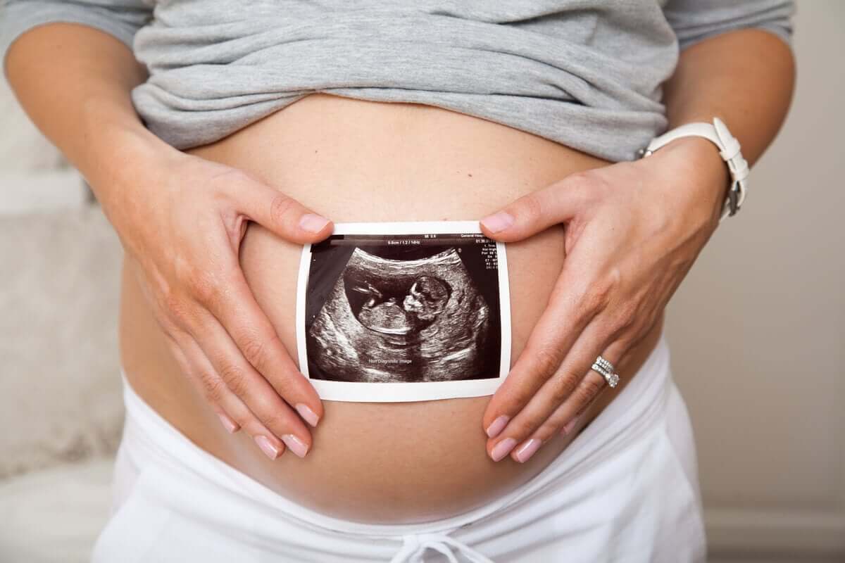 A pregnant woman holding an ultrasound picture over her belly.