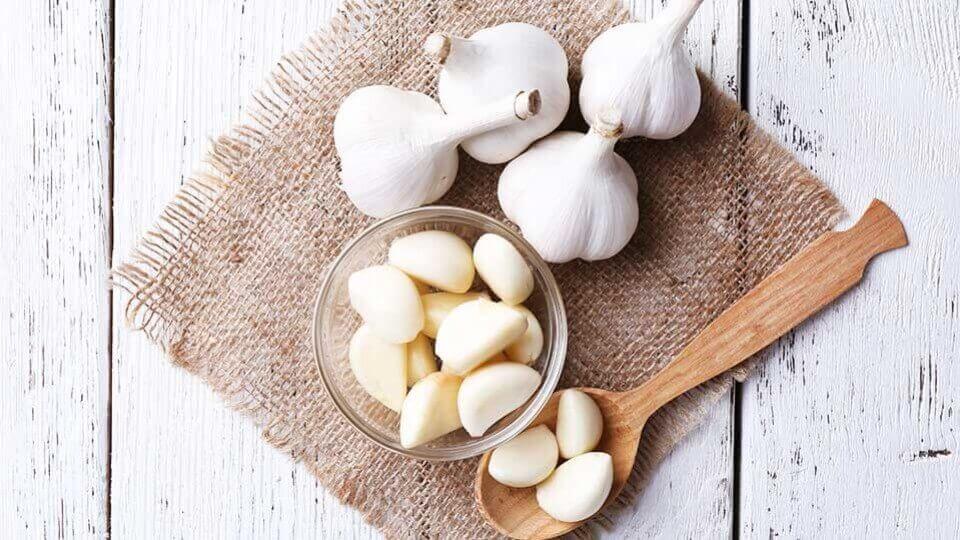 Four heads of garlic and a bowl of peeled garlic cloves.