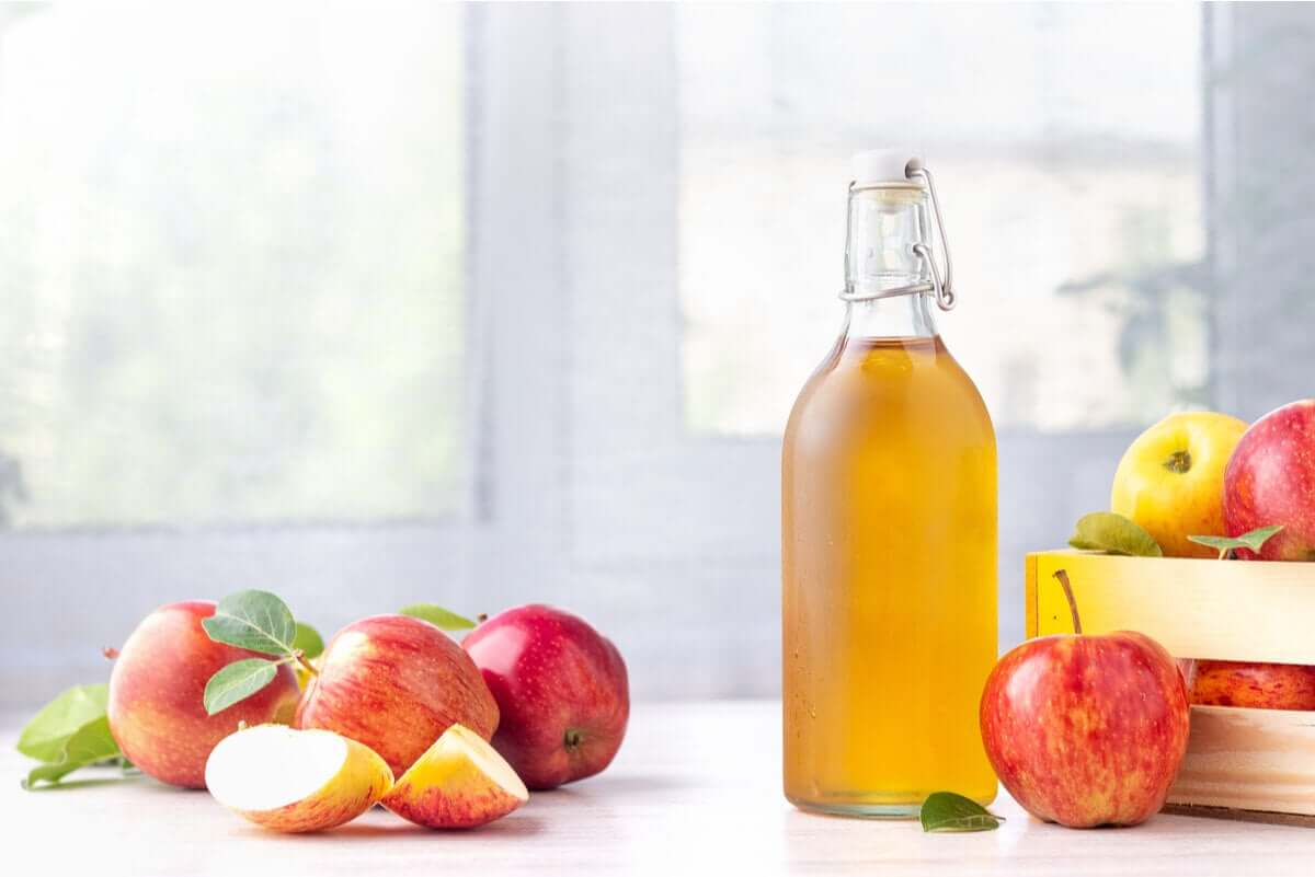 Apples and a glass bottle of apple cider vinegar.