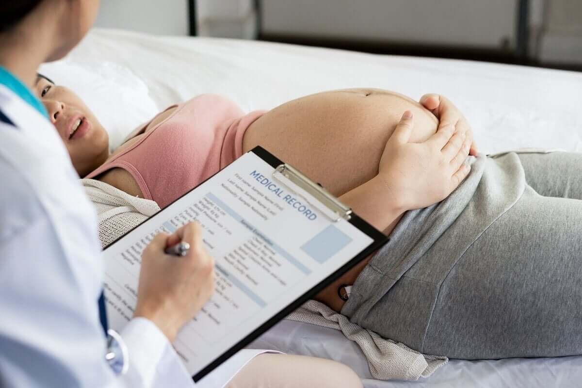 A pregnant woman in a hospital bed talking to her doctor.