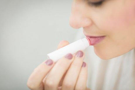 A woman applying lip balm.