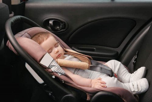 A baby asleep in a car seat.