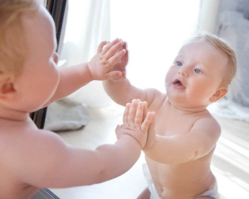 A baby in front of the mirror.