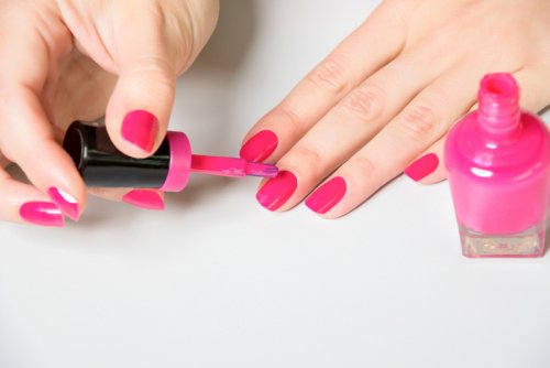 A hand painting the nails of the other hand.