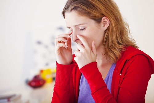 A woman holding her nose in pain.