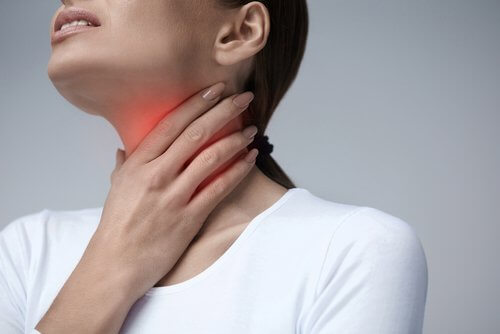 A woman holding her throat in pain.
