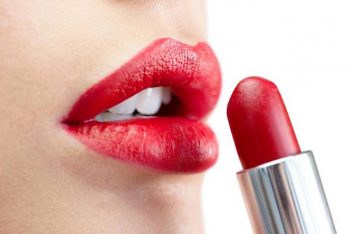 A woman painting her lips.