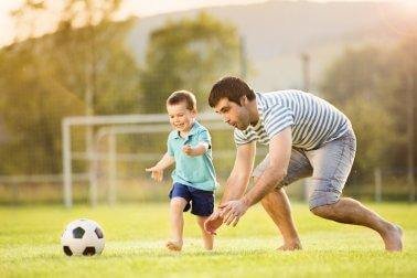 A boy playing soccer with his dad.