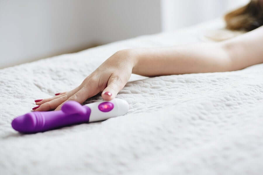 A woman reaching for her vibrator in bed.