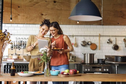 Women cooking chicken breasts in cheese sauce in the kitchen.