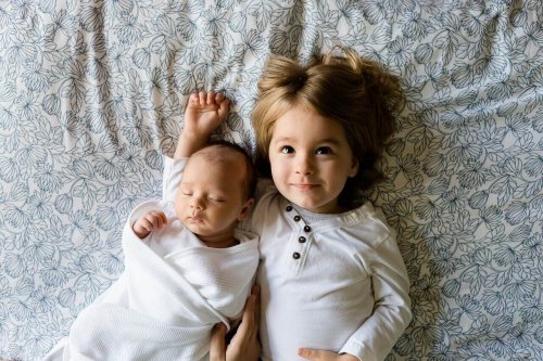 A baby and a toddler lying in bed.