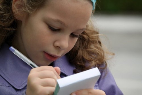 A girl writing on a notepad.