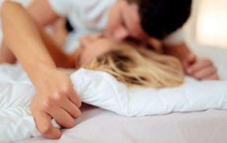 A couple kissing in bed.