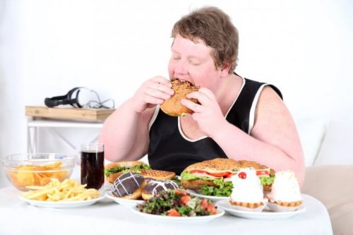 Obese man eating lots of food whole buffet on the table unhealthy food hunger and anxiety