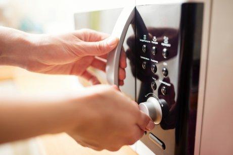 A person using a microwave to disinfect their kitchen sponges.