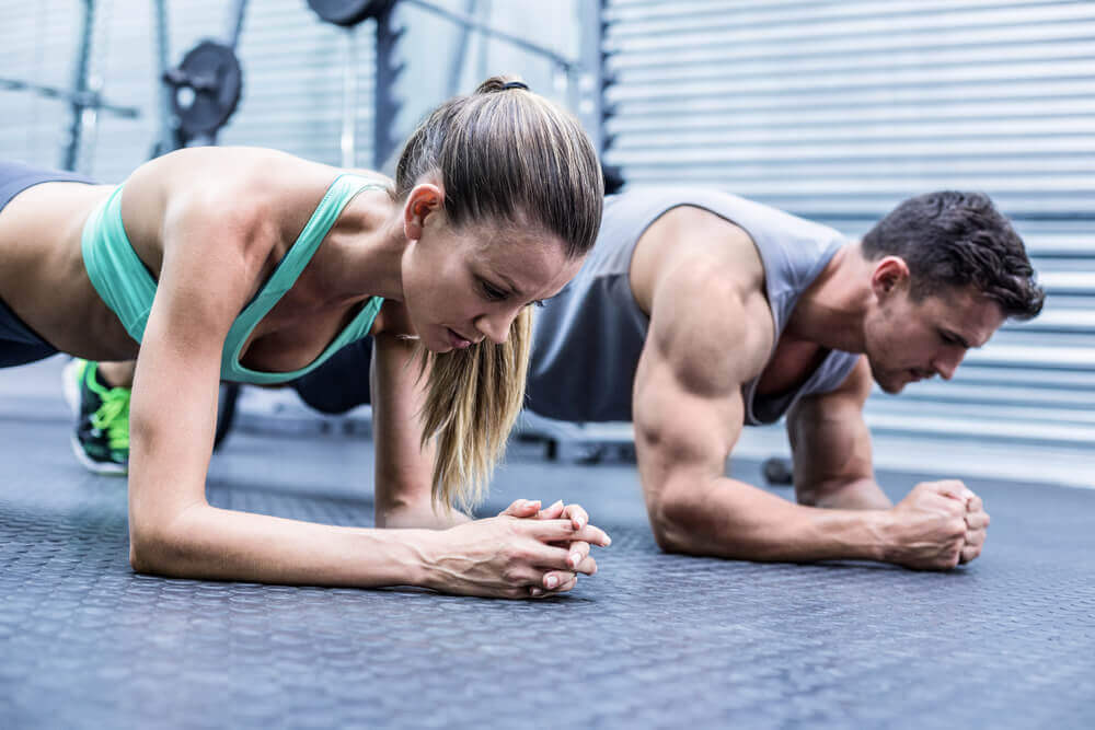 A man and woman doing planks at the gym.