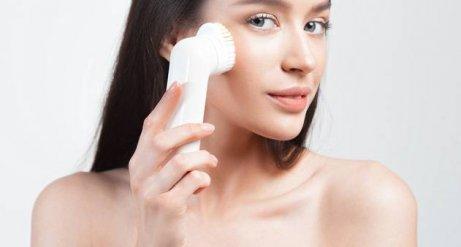 A woman using a facial brush.