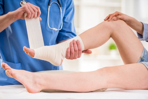 A doctor bandaging a person's ankle.