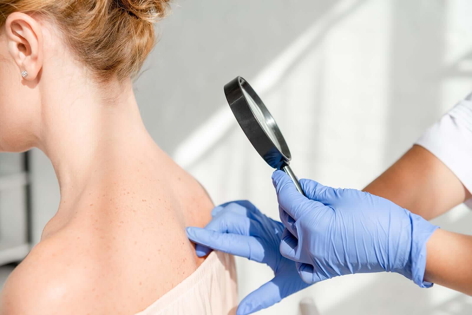 A dermatologist examining the skin on a woman's back.