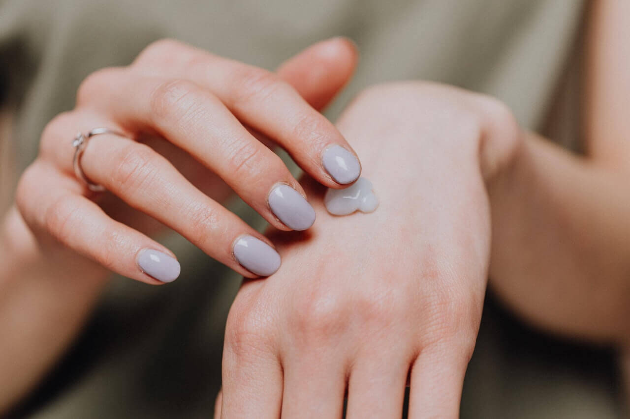 A woman applying moisturizer to her hands.