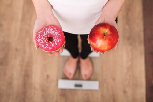 A woman deciding between her sugar cravings and an apple.