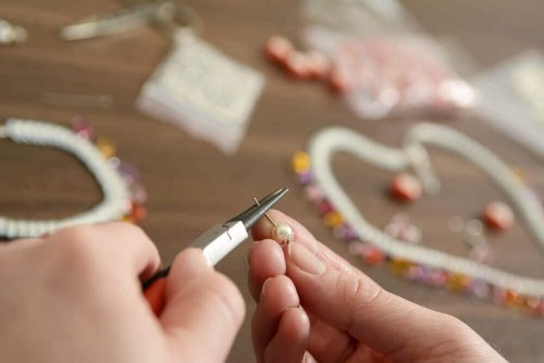 A person making homemade keychains with beads and wire..