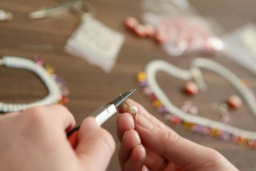 A person making homemade keychains with beads and wire..