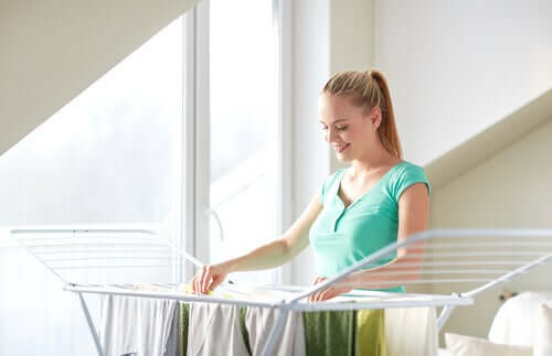 A woman hanging clothes on a drying rack.